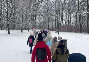 uczniowie klas drugich idą przez zaśnieżony park