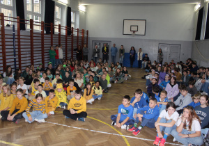 sala gimnastyczna pełna uczniów ubranych w określonych kolorach